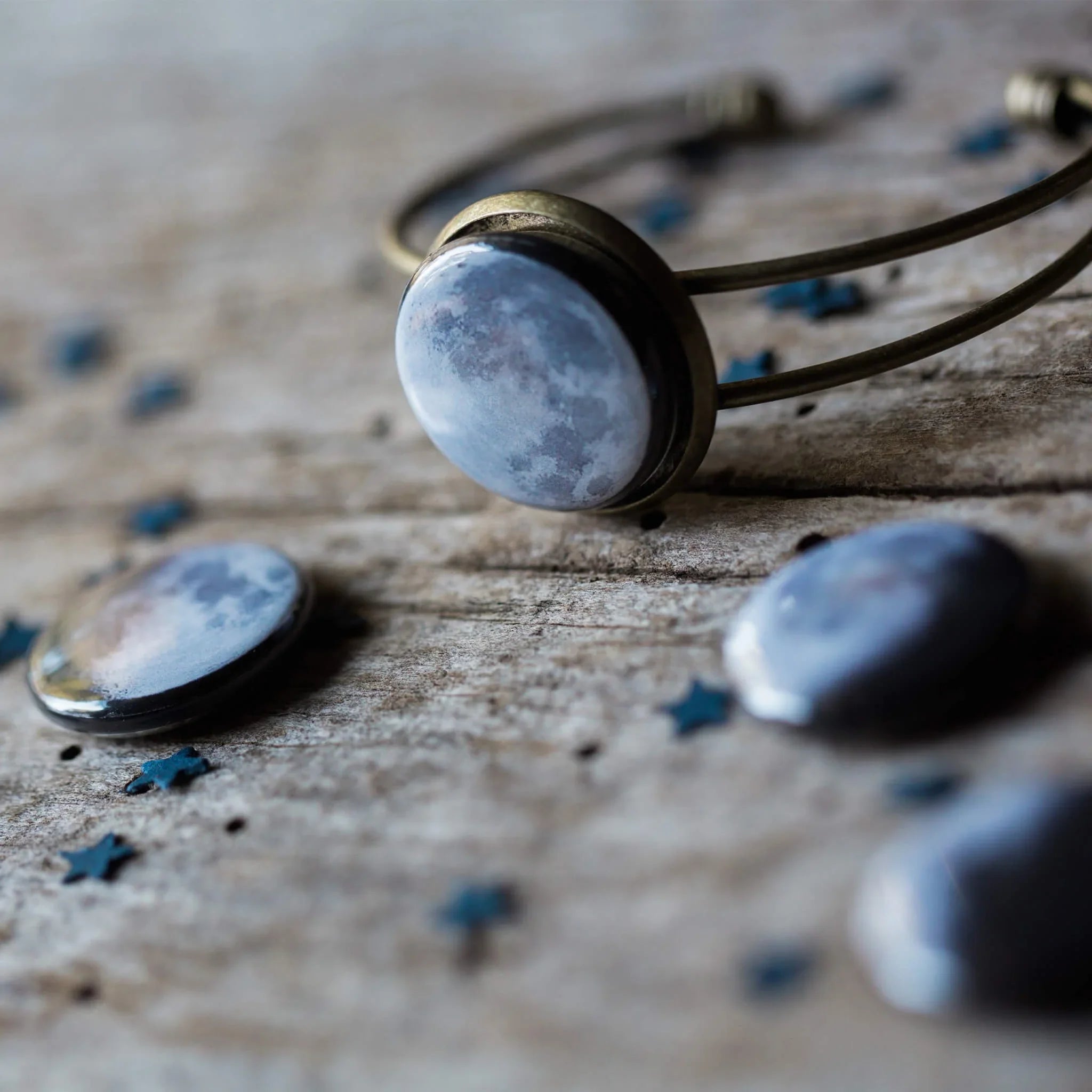 Moon-themed jewelry bracelet and cabochons on rustic wooden surface with small star decorations