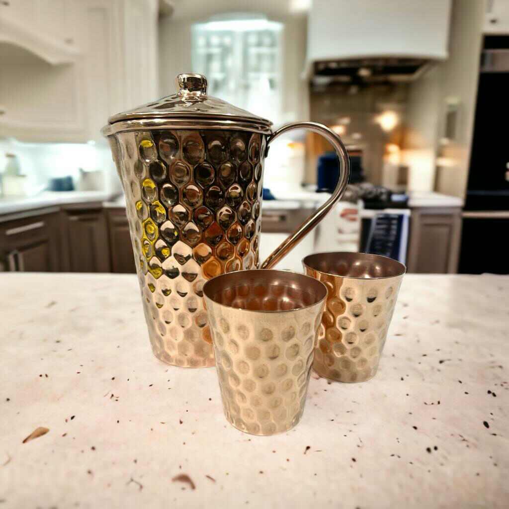 Hammered gold metal pitcher and cups on marble counter, Qu!rk Boutique kitchenware