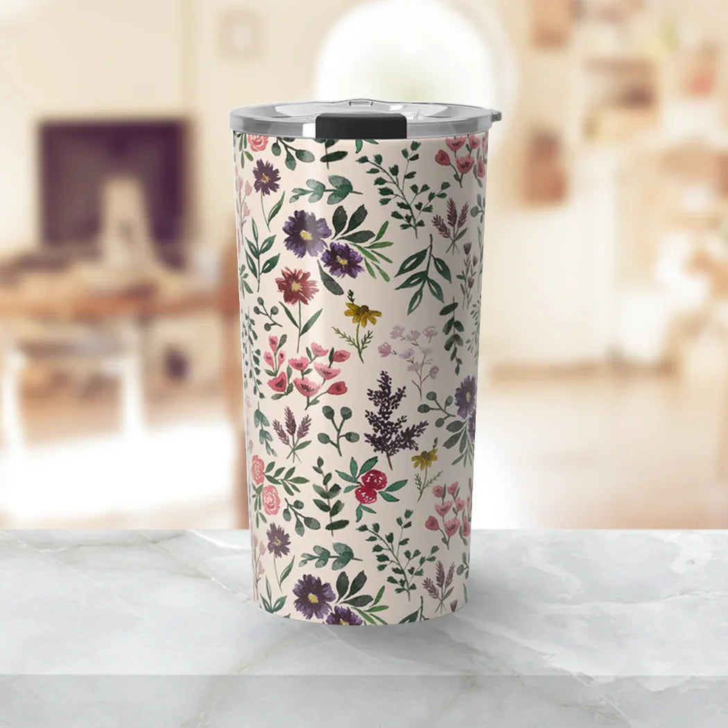 Floral patterned stainless steel tumbler with silver lid on marble table in cozy living room