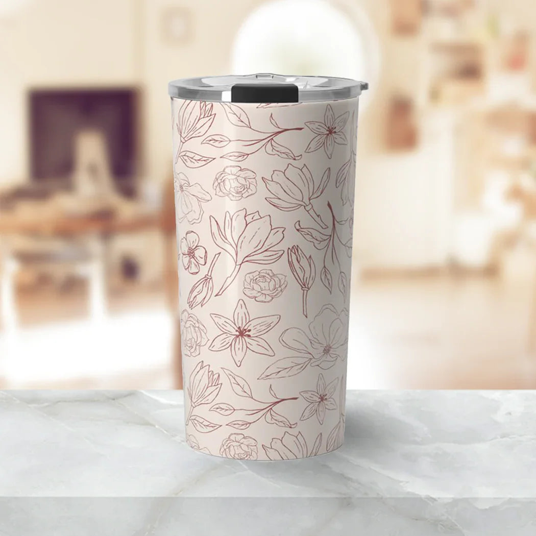 Pink travel tumbler with floral line art design and clear lid on marble surface