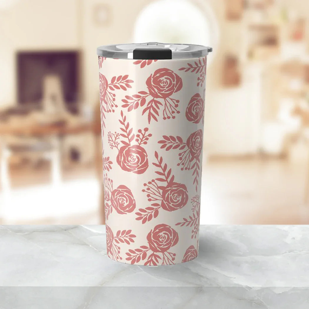 Tall insulated tumbler with pink rose floral pattern on white, stainless steel lid, on marble surface