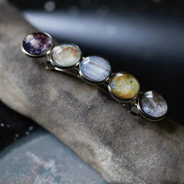 Hair clip featuring five round glass cabochons with detailed planet and galaxy designs