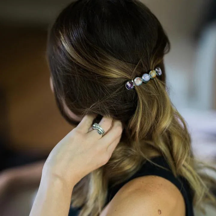 Woman with brown and blonde hair wearing a celestial planet-themed hair clip and silver rings