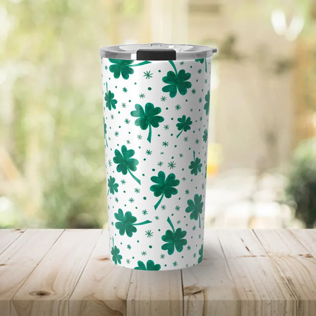 White insulated tumbler with green shamrock and star patterns on wooden surface