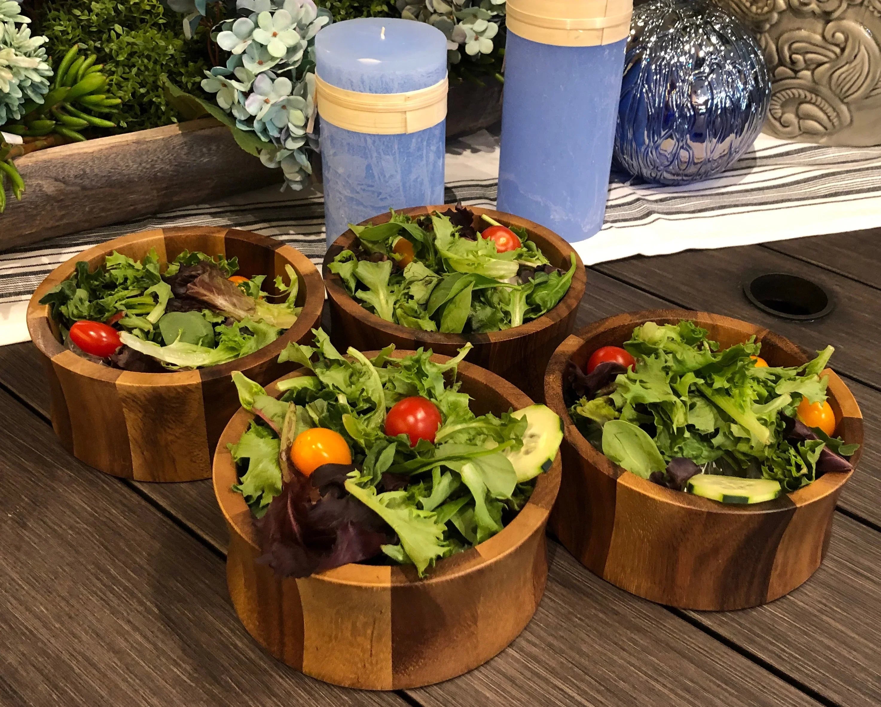 Fresh garden salads in wooden bowls with candles and floral decor on rustic table, Qu!rk Boutique style
