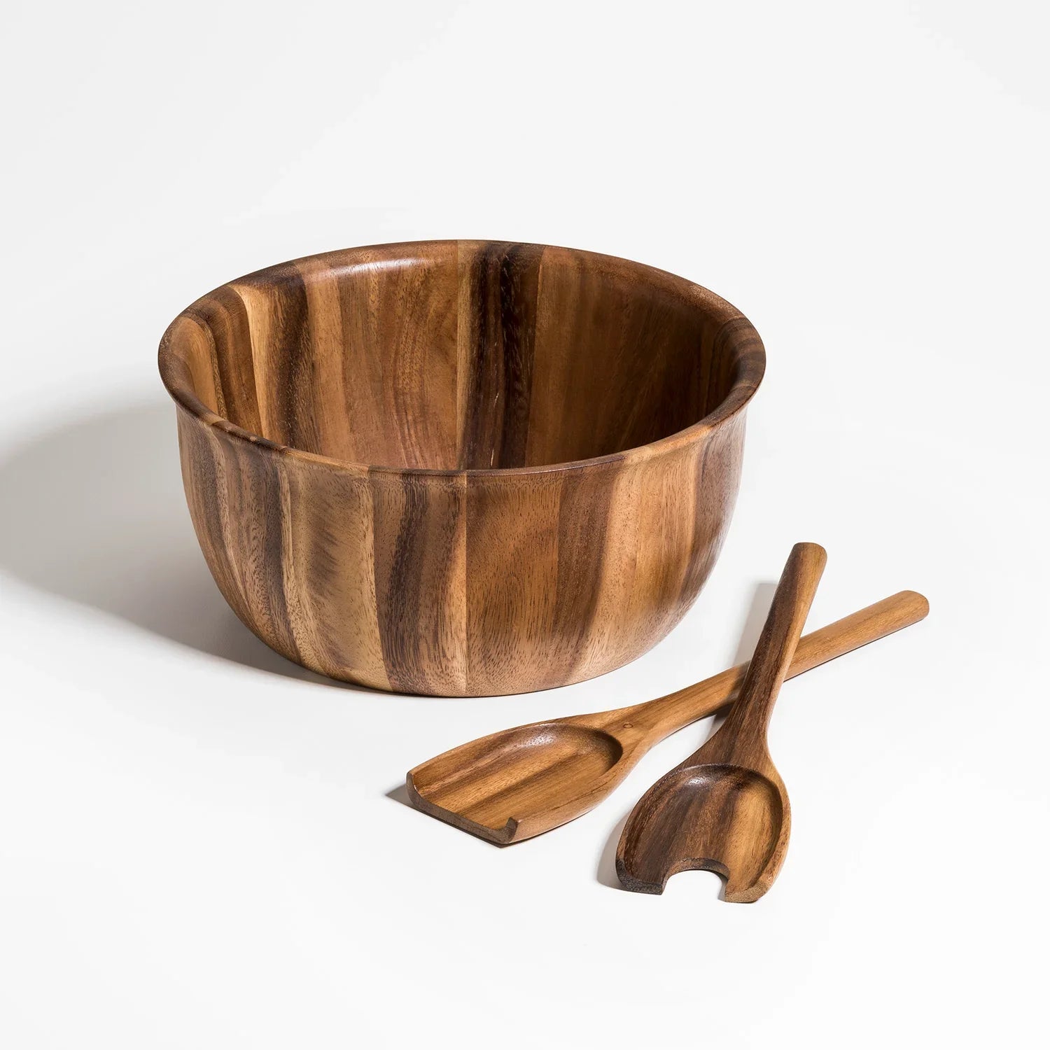 Handcrafted wooden salad bowl with matching serving utensils on white background