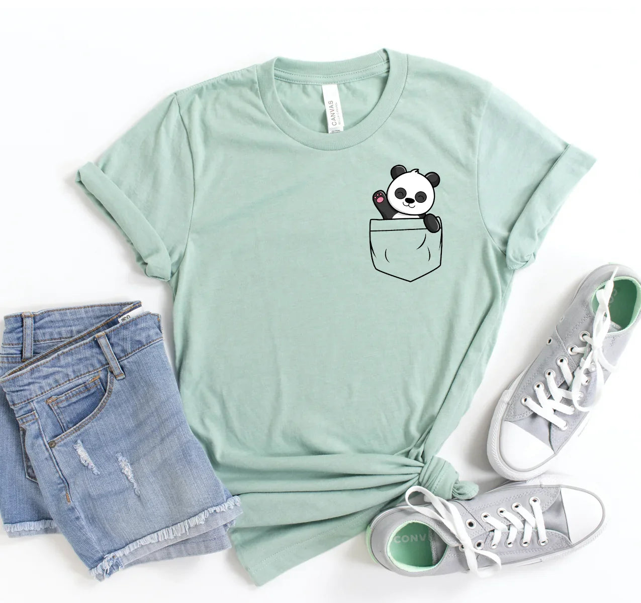Light green t-shirt with cute cartoon panda waving from a printed chest pocket, paired with denim shorts and gray sneakers