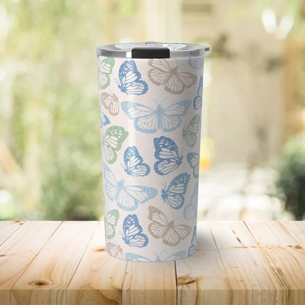 Insulated travel tumbler with blue, green, and beige butterfly pattern on wooden table