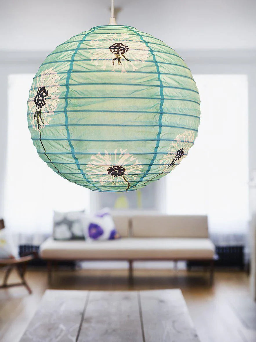 Aqua paper lantern with white dandelion designs hanging in a bright modern living room