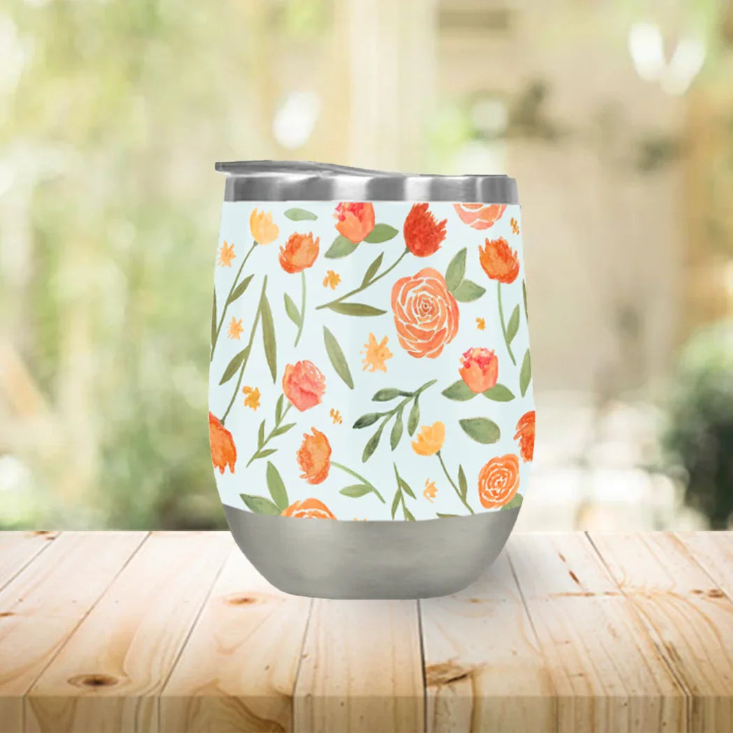 Floral insulated tumbler with orange and green botanical art on wood table at Qu!rk Boutique