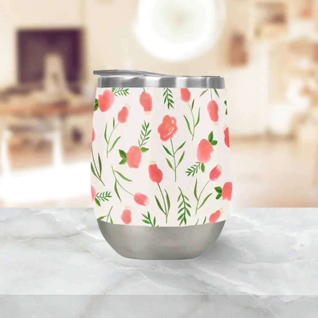 Floral stainless steel tumbler with pink and green artist-designed pattern on marble counter