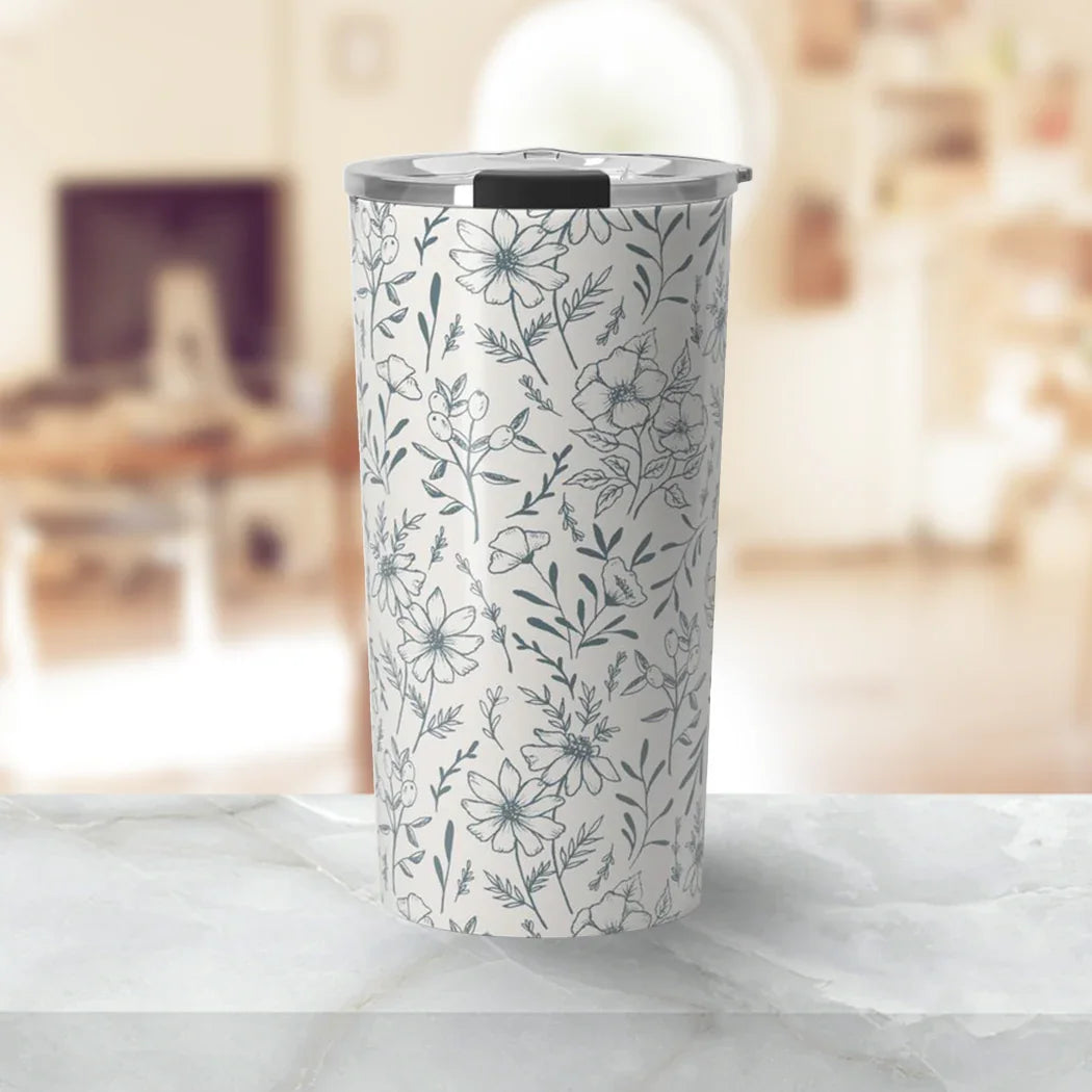 White travel tumbler with black and gray floral pattern on marble countertop in cozy room