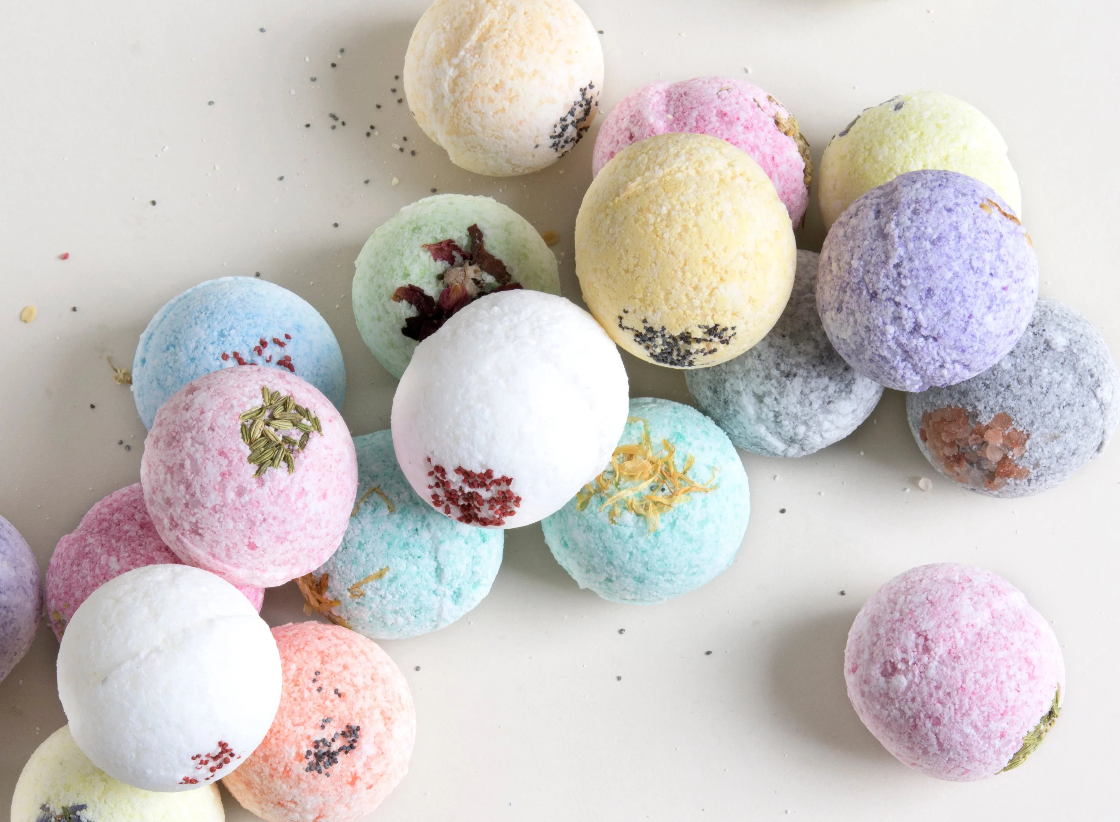 Assorted colorful bath bombs with botanical and salt accents on white background