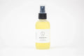 Clear bottle of Lizush natural massage oil with black spray cap on white background
