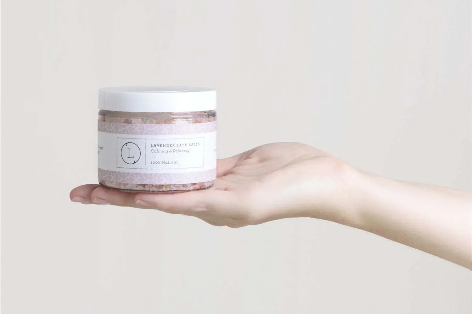 Hand holding a jar of 100% natural lavender bath salts with calming and relaxing label