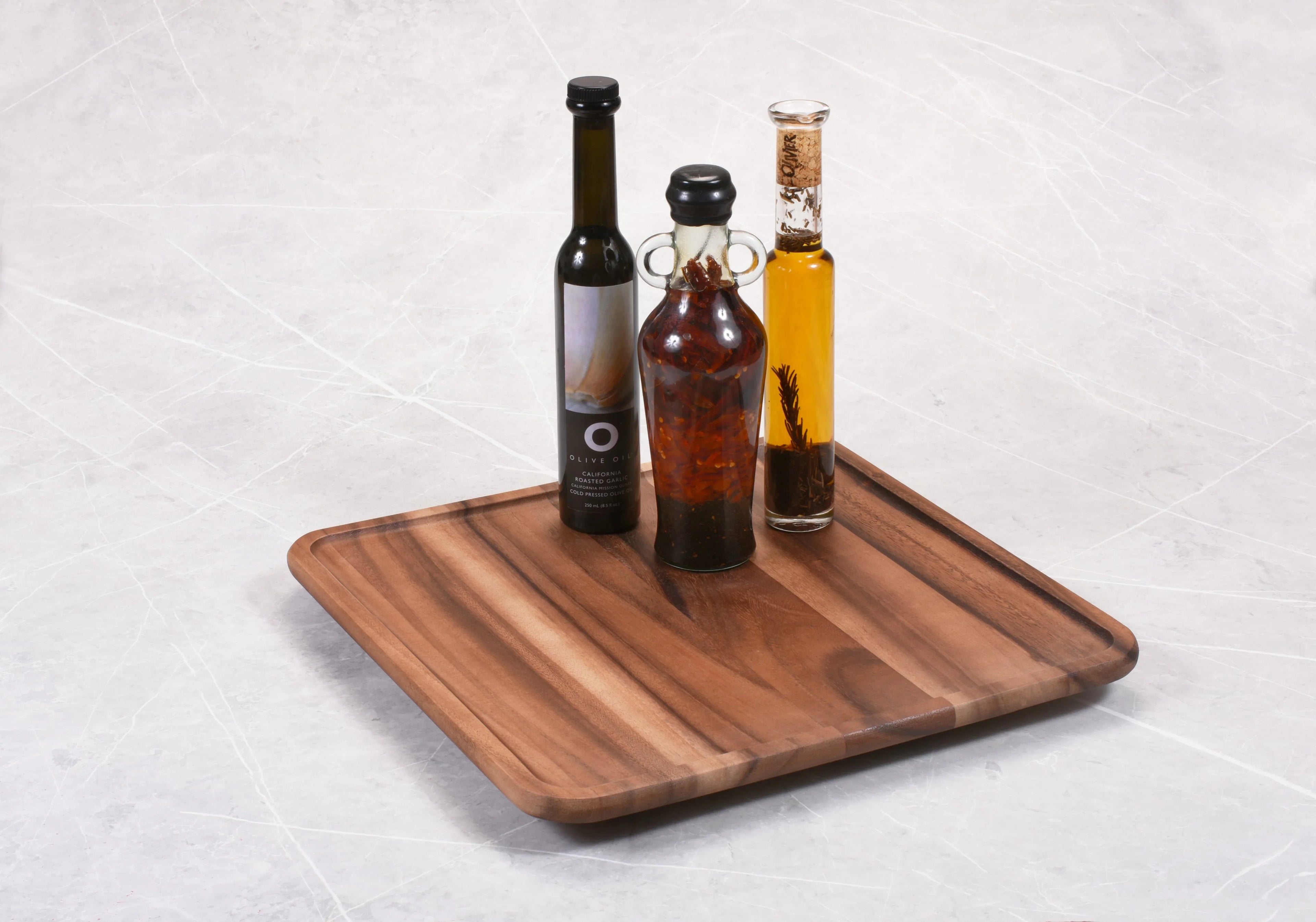 Three artisanal oil bottles on a square wooden tray, Qu!rk Boutique gift shop aesthetic