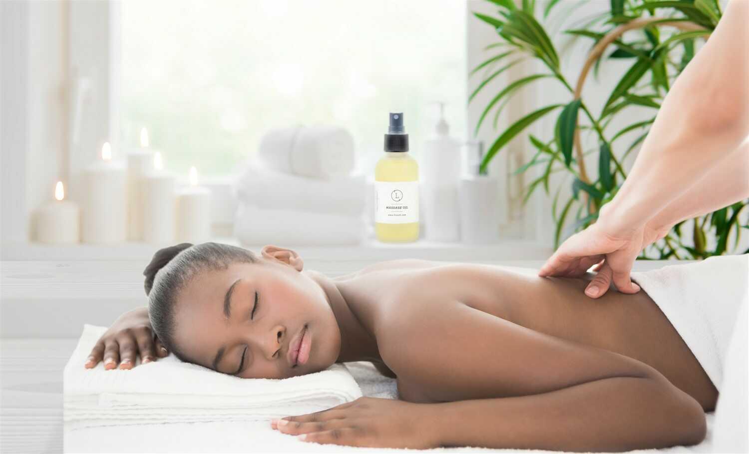 Relaxed woman receiving massage in spa with massage oil, candles, and green plant background
