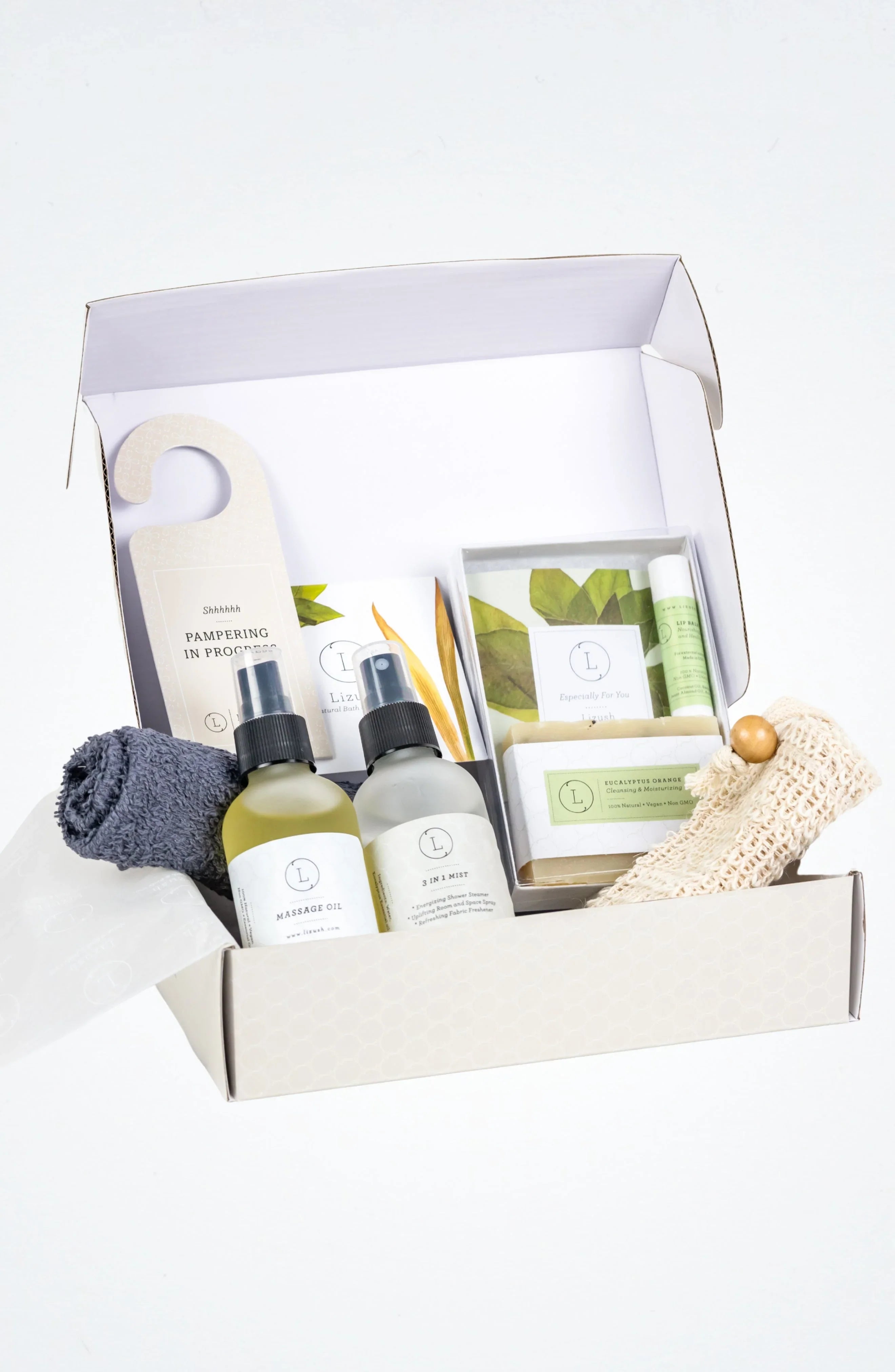 Open wellness gift box with massage oil, 3 in 1 mist, eucalyptus soap, lip balm, towel, and exfoliating mitt