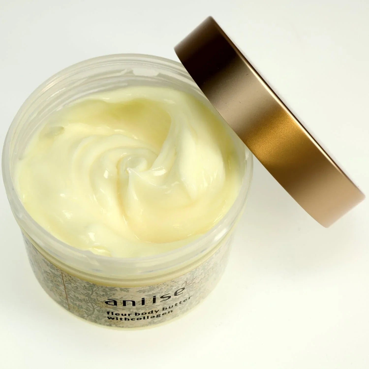 Open jar of anilse moisturizing body butter cream with collagen, gold lid, on white background.
