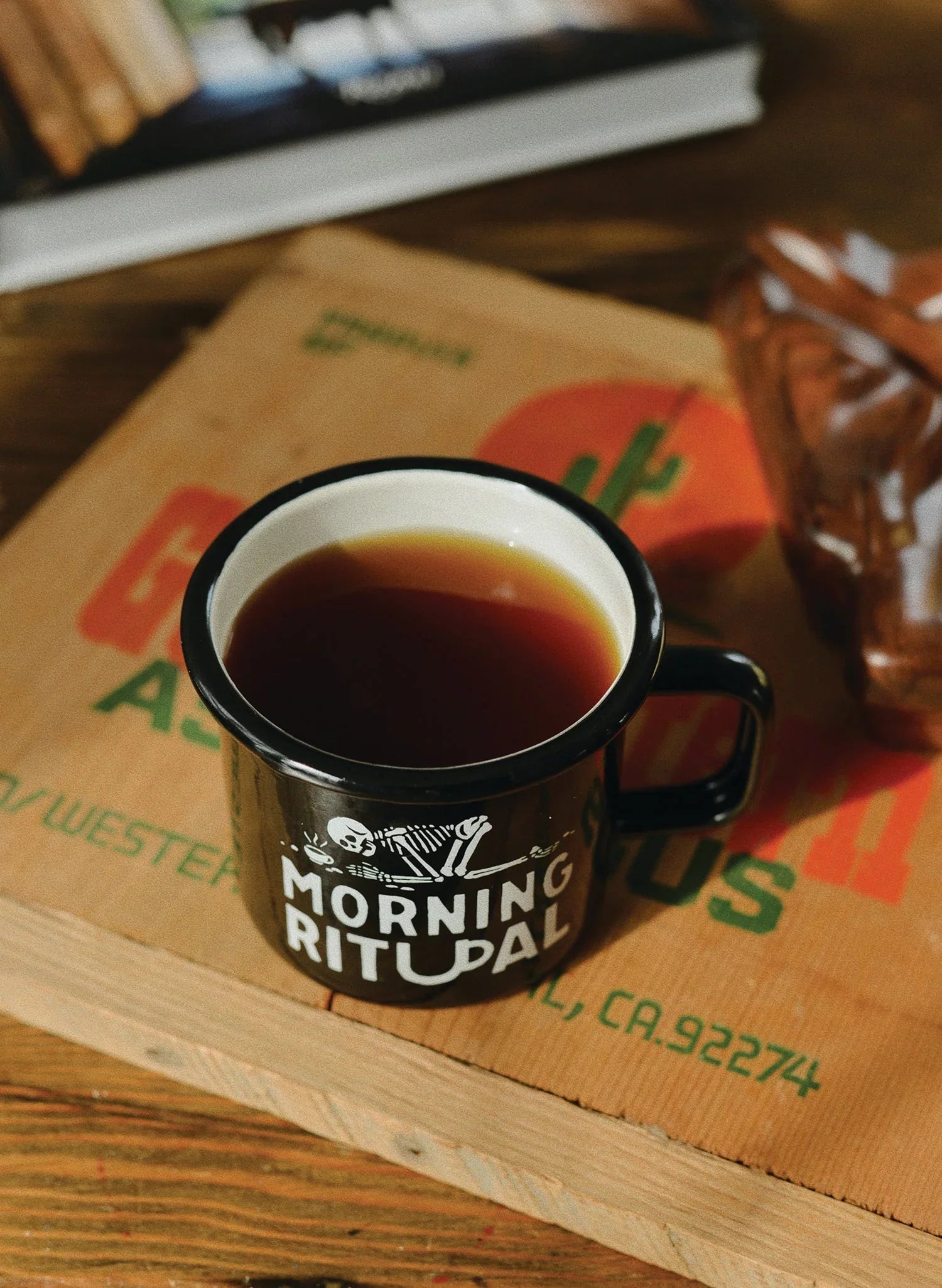 Black Morning Ritual mug with coffee on a rustic table at Qu!rk Boutique
