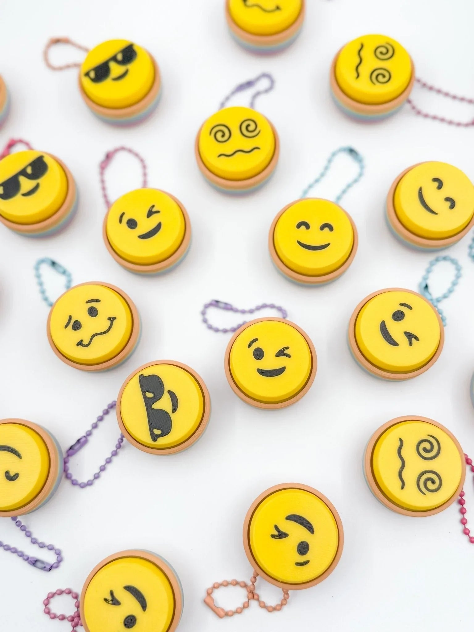 Assorted emoji keyboard clickers with yellow faces and colorful chains on white background, Qu!rk Boutique