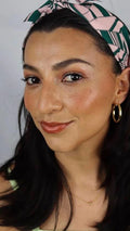 Woman with glowing skin, gold hoop earrings, and a patterned headband, Qu!rk Boutique style