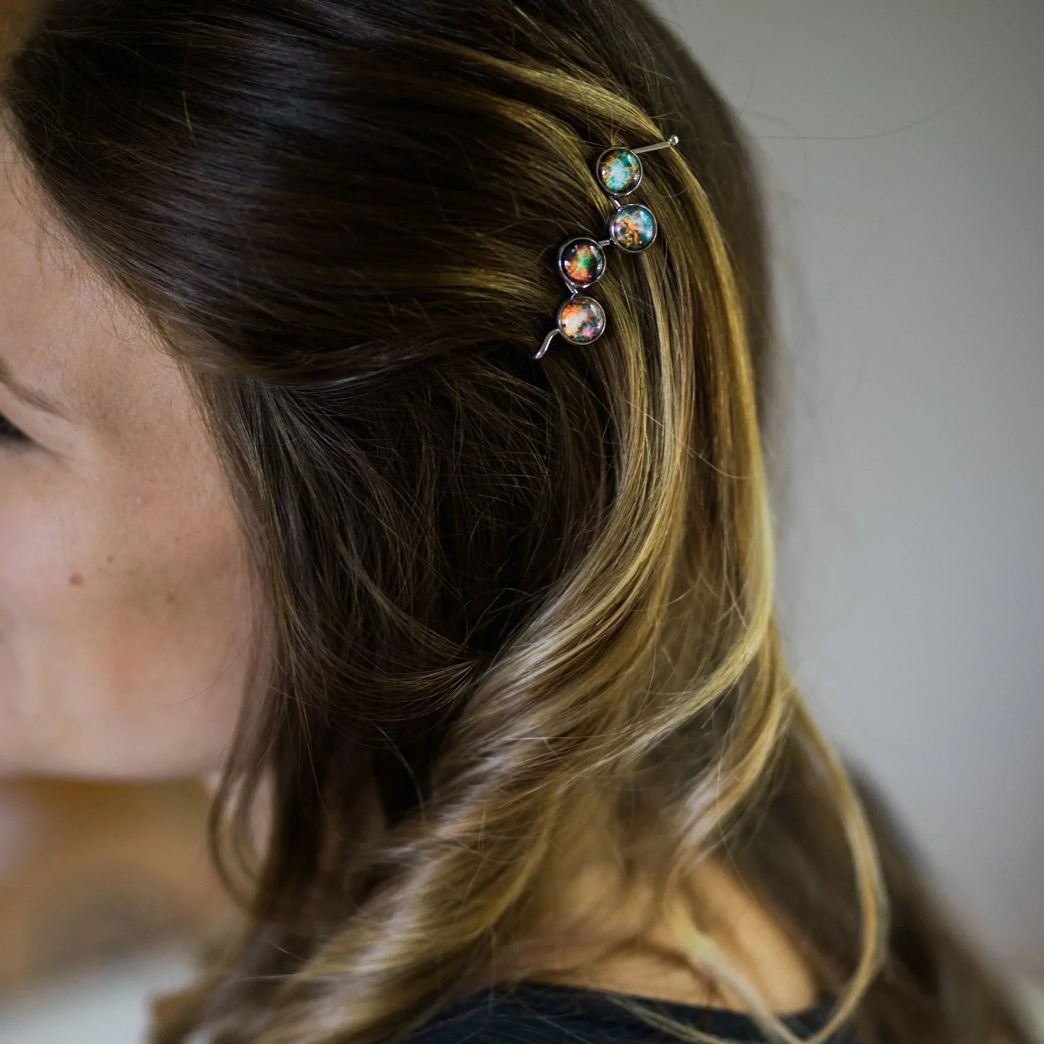 Woman wearing cosmic-inspired colorful hairpin, shown in close-up, at Qu!rk Boutique