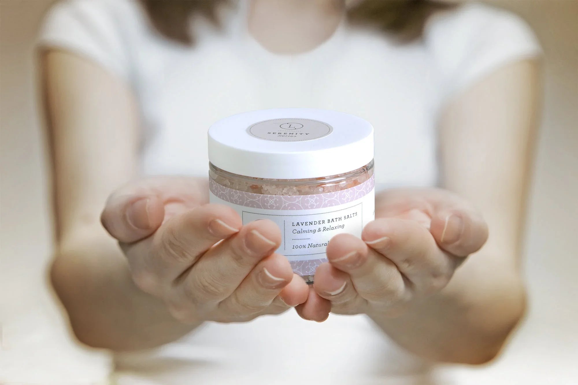 Person holding jar of natural lavender bath salts with calming and relaxing label