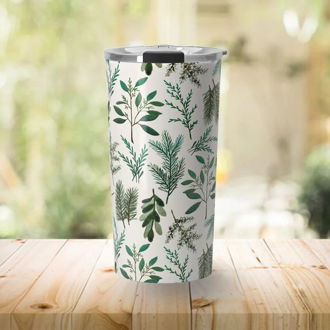 Tall tumbler with green botanical leaf pattern and silver lid on wooden table