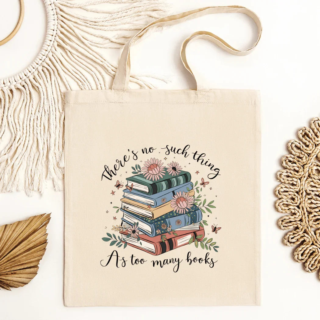 Beige tote bag with stack of colorful books, flowers, and text 'There's no such thing as too many books'
