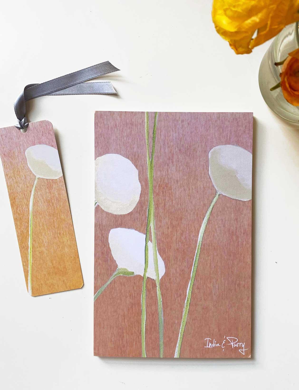 Cream floral notepad and matching bookmark set on white surface with orange flowers