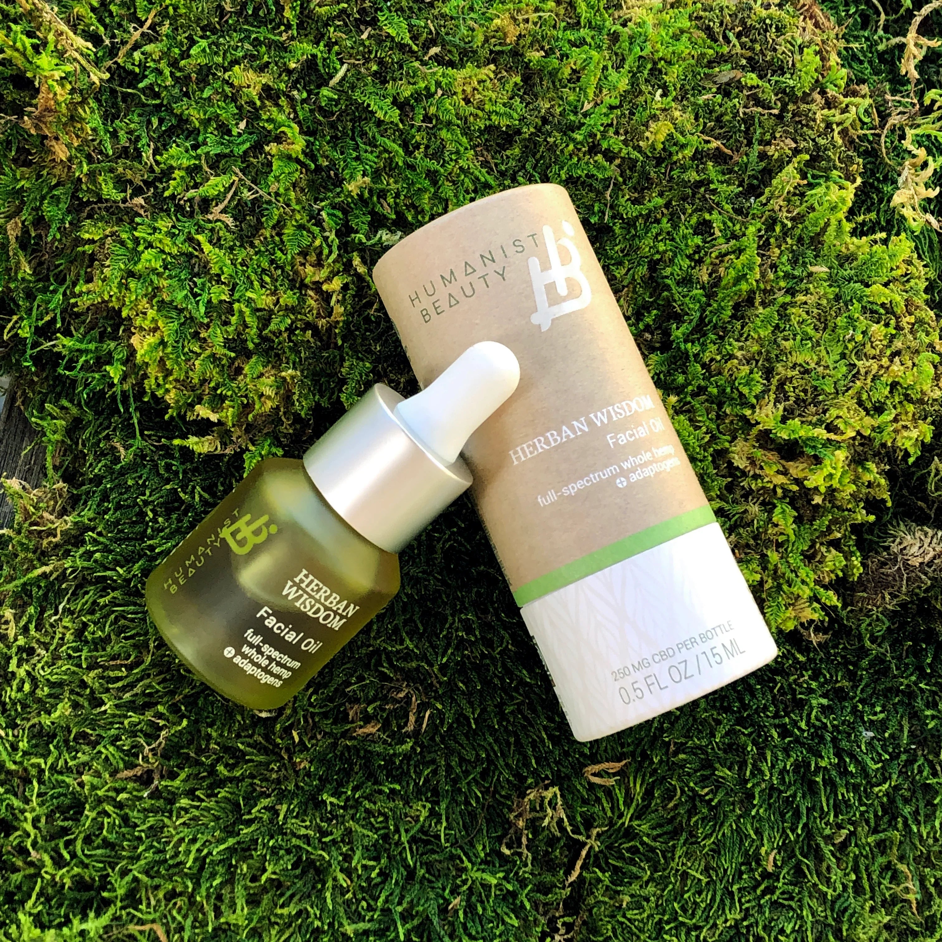 Herban Wisdom facial oil by Humanist Beauty on green moss, eco-friendly skincare at Qu!rk Boutique