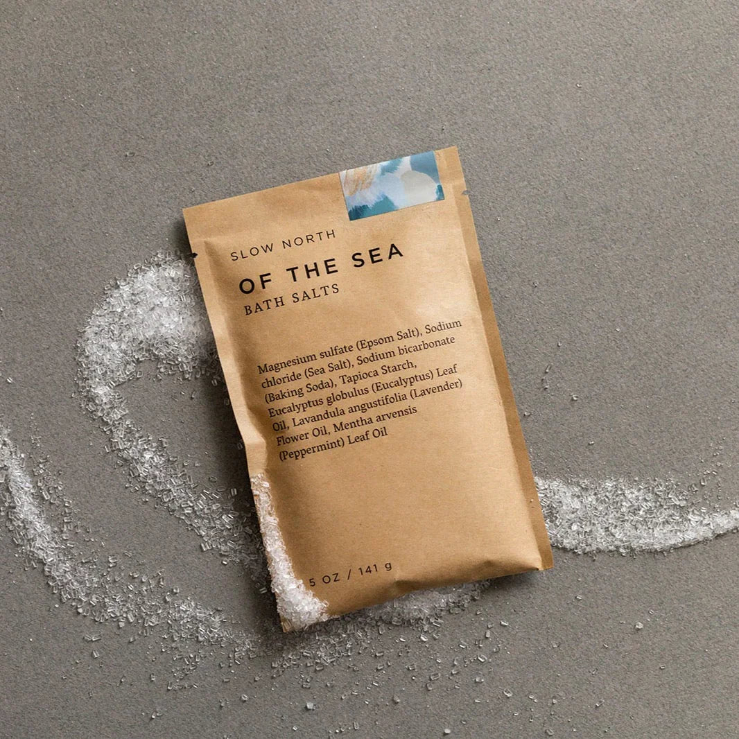 Of the Sea bath salts pouch by Slow North on gray background with scattered sea salt crystals
