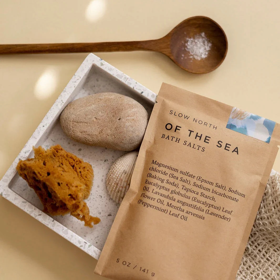 Of the Sea bath salts pouch with natural sponge, stone, seashell, and wooden spoon on tray