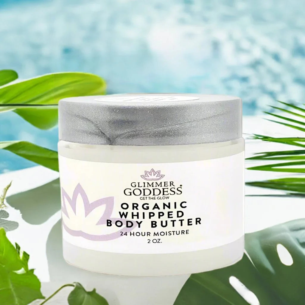 Glimmer Goddess Organic Whipped Body Butter 2 oz jar with tropical leaves and blue water background