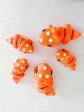 Oversized chunky orange triceratops toys on a white surface, quirky boutique gift idea