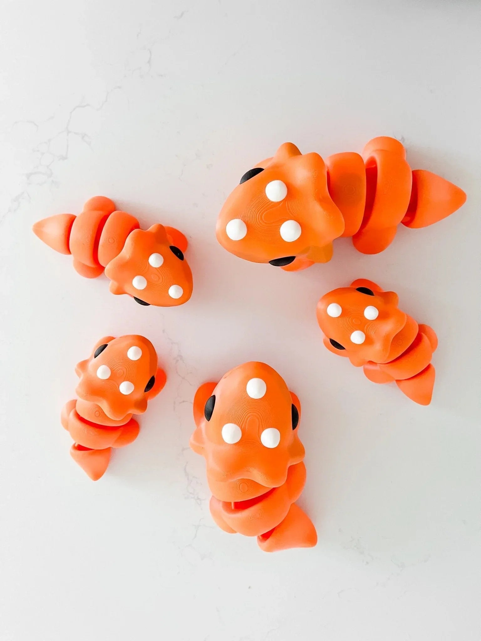 Oversized chunky orange triceratops toys on a white surface, quirky boutique gift idea