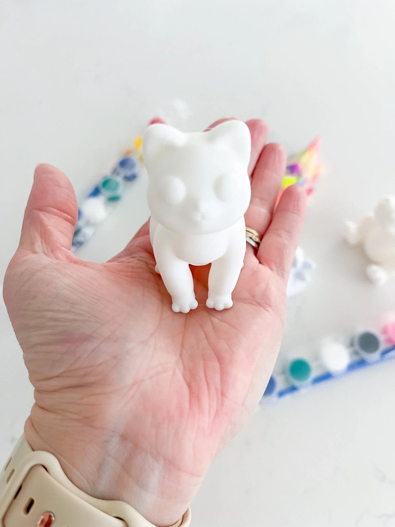 Hand holding blank cat figurine from DIY pick and paint kit at Qu!rk Boutique