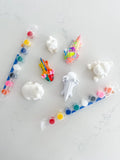 Pick and paint kit with unpainted animal figurines, colorful paints, and brushes on white background