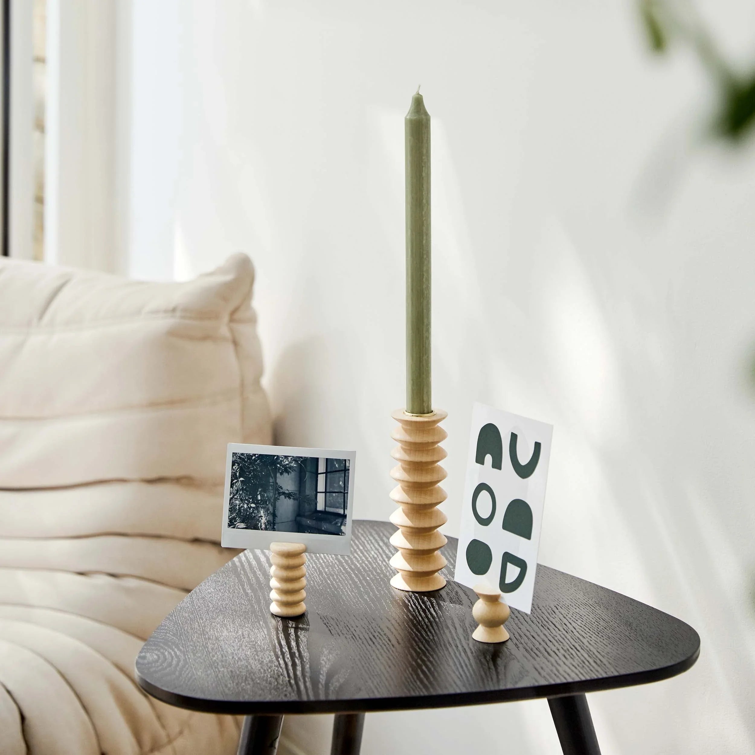Modern wooden postcard and photo holders with green candle on black table, stylish home decor