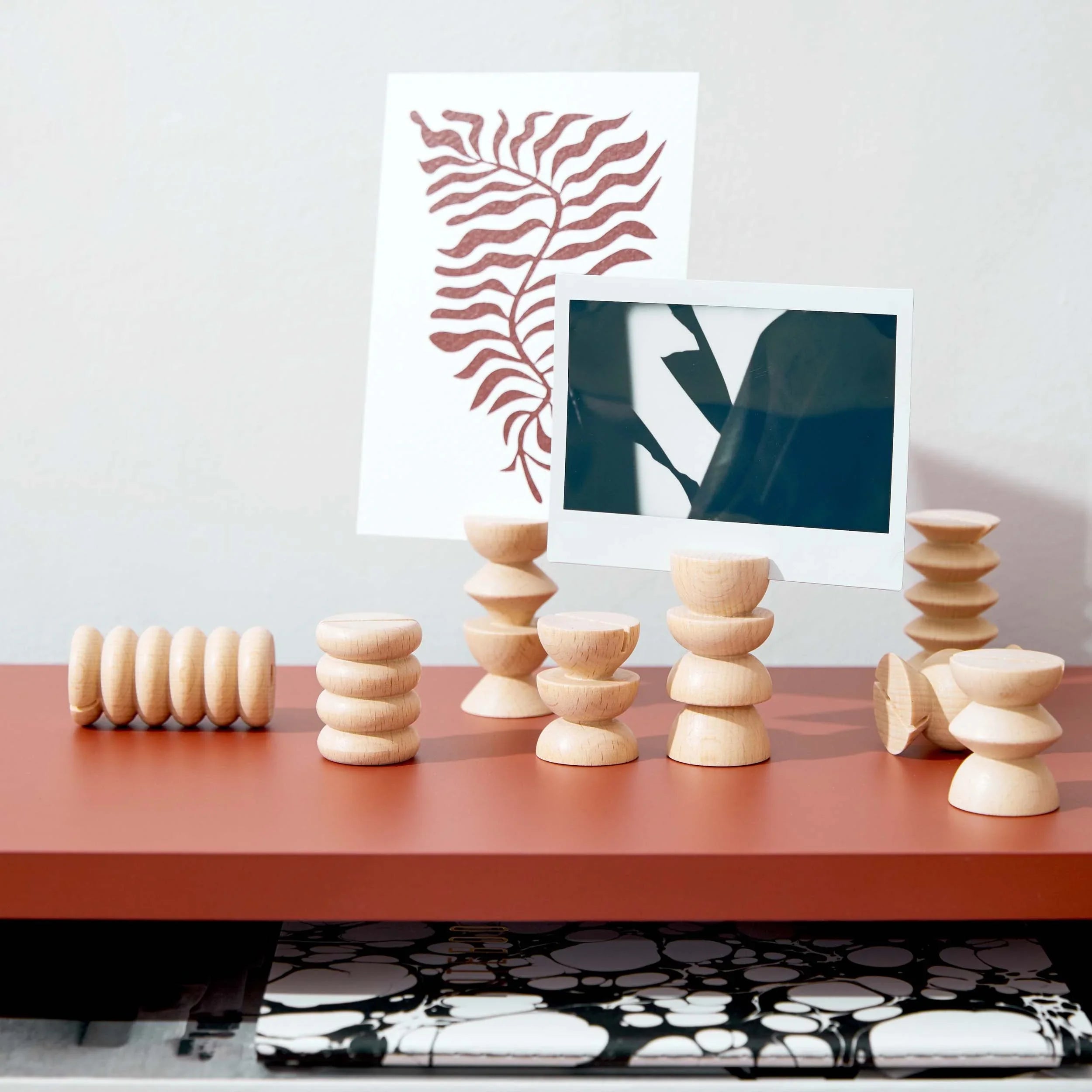 Modern wood postcard holders displaying art prints on a rust-colored desk, Qu!rk Boutique decor