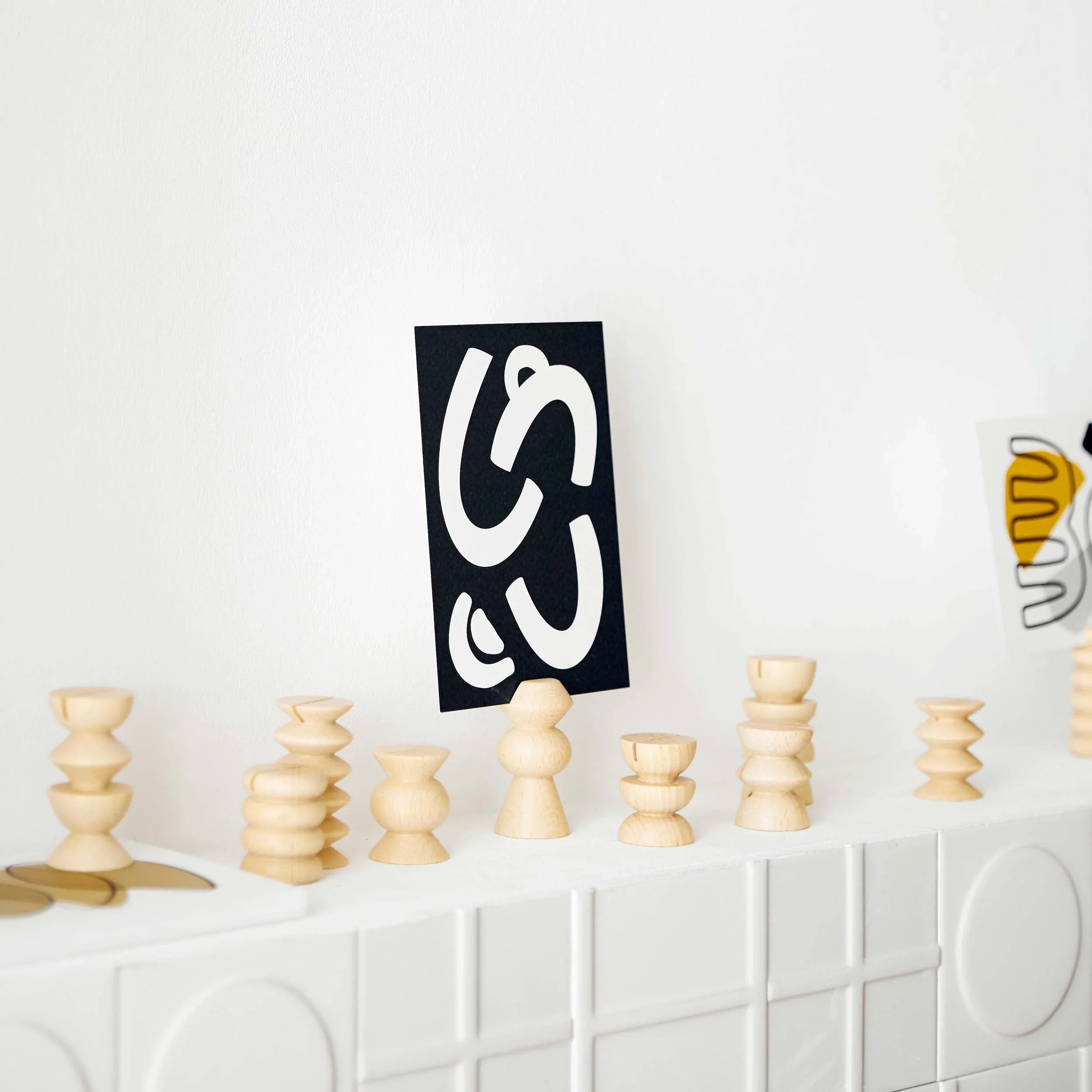 Modern wooden postcard stands display abstract art cards on a white shelf, Qu!rk boutique decor