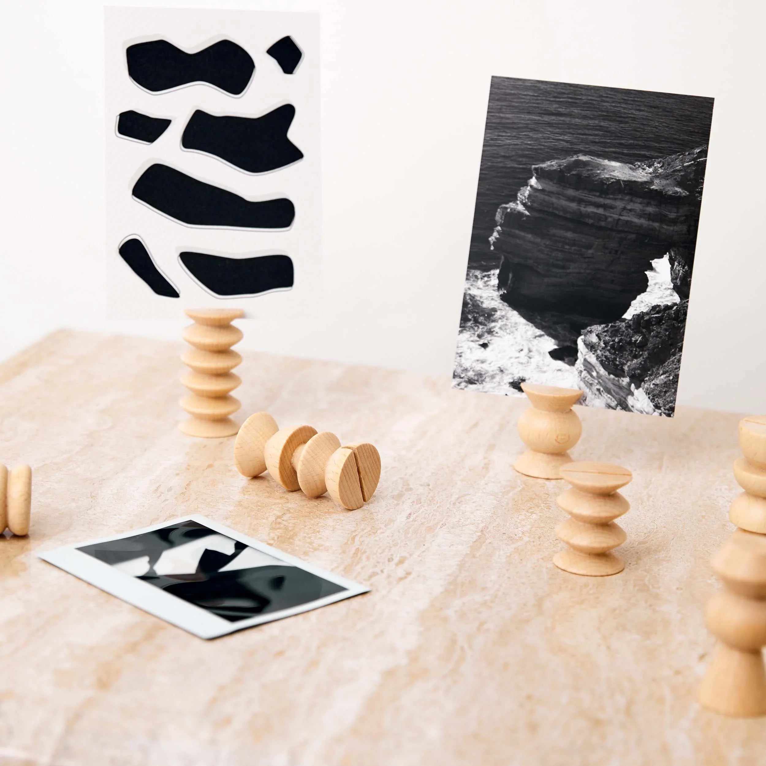 Modern wooden postcard holders displaying black-and-white art prints on a marble desk
