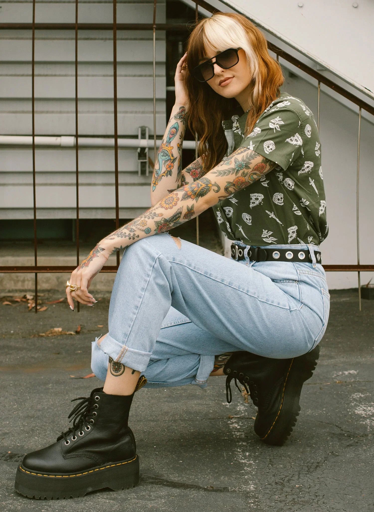 Tattooed woman in skull print shirt, mom jeans, and platform boots at Qu!rk Boutique