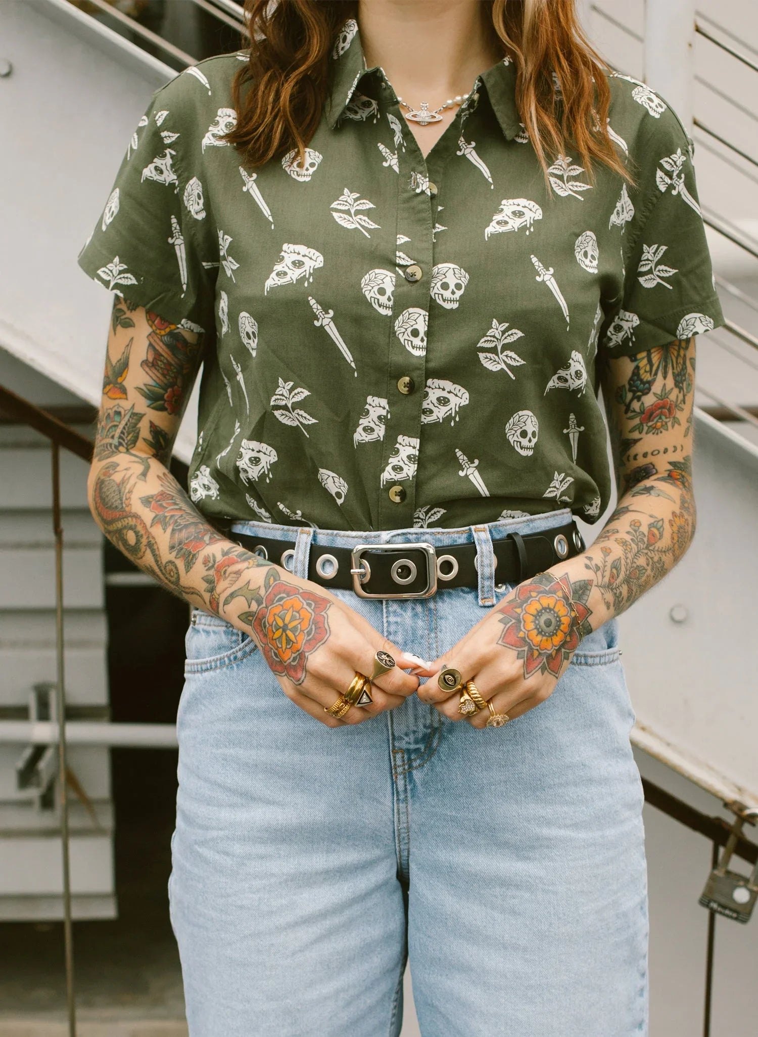 Tattooed woman in green pizza-print button up shirt and light denim jeans at Qu!rk Boutique