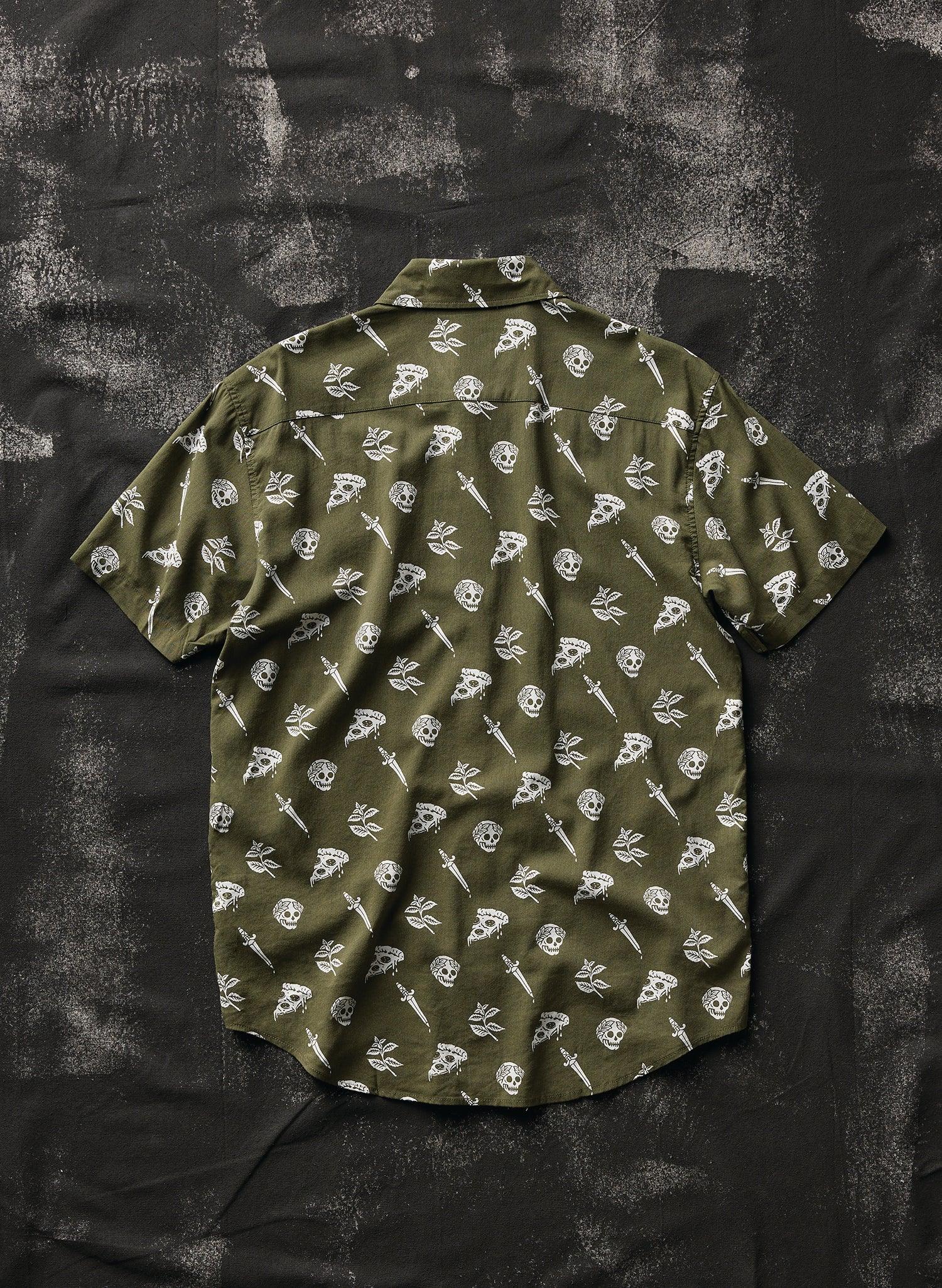 Olive green button-up shirt with white tattoo-inspired skull, dagger, and pizza slice print, laid flat.