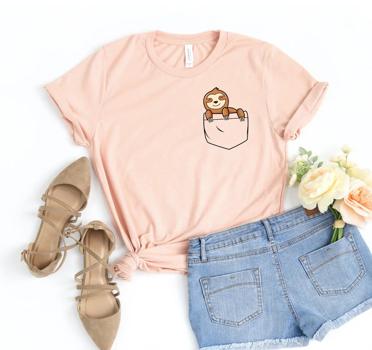 Light pink t-shirt with a cartoon sloth peeking out of a pocket, paired with blue denim shorts and beige strappy shoes