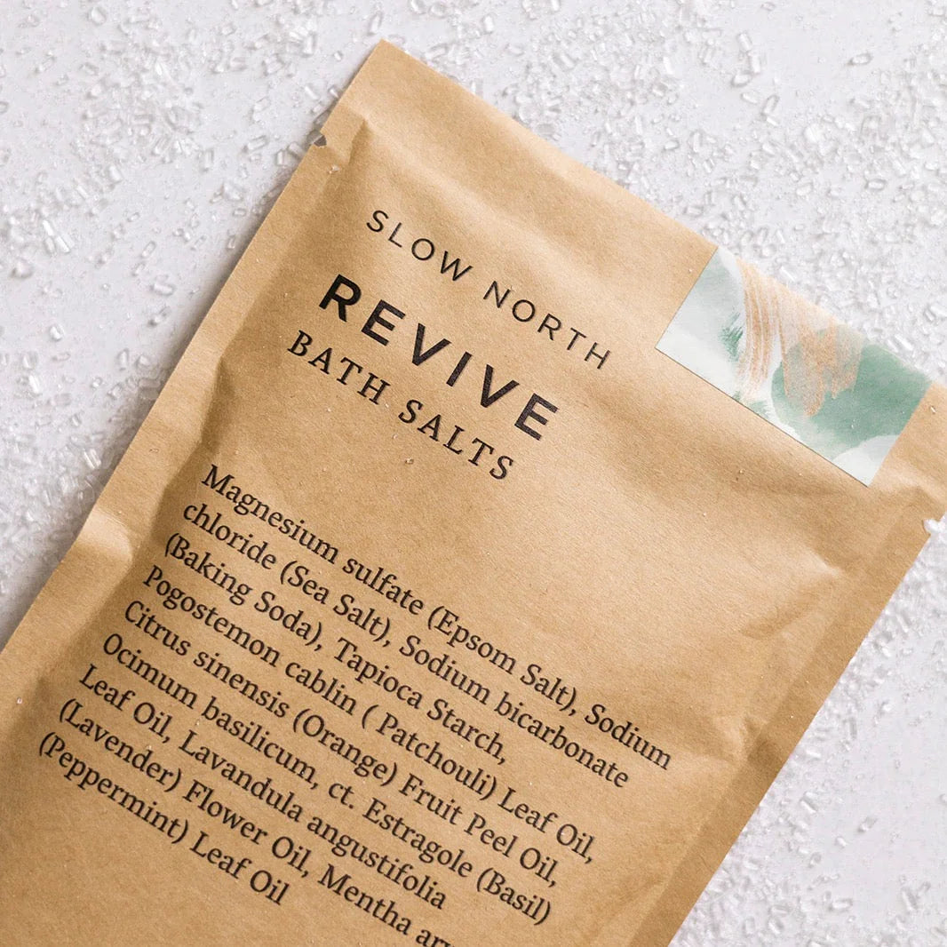 Slow North Revive bath salts pouch on a light surface with visible salt crystals, eco-friendly gift