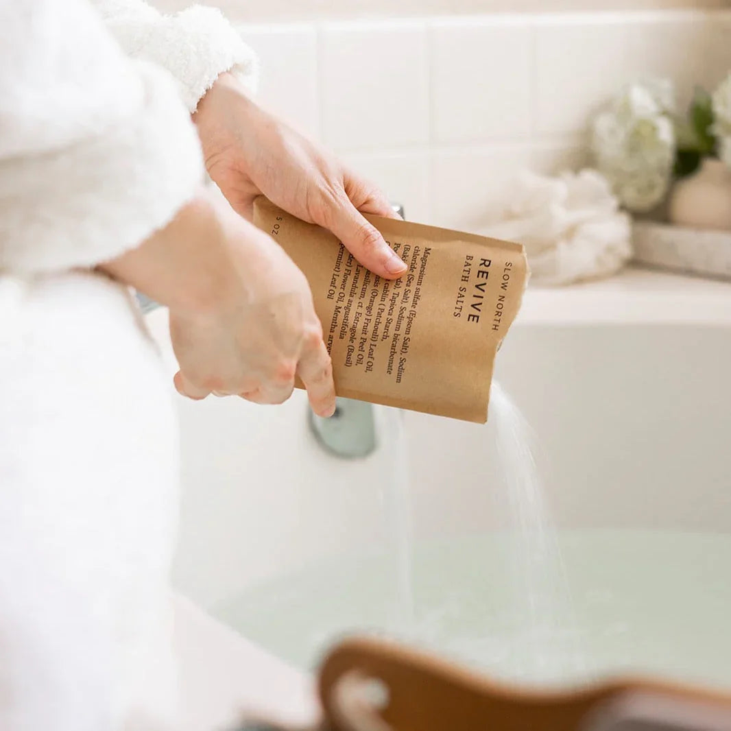 Woman pours Slow North Revive bath salts into bathtub at Qu!rk Boutique, eco-friendly spa gift
