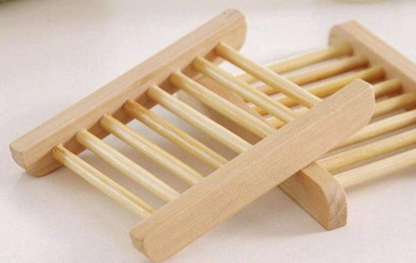 Two wooden soap dishes with slatted design on a white surface